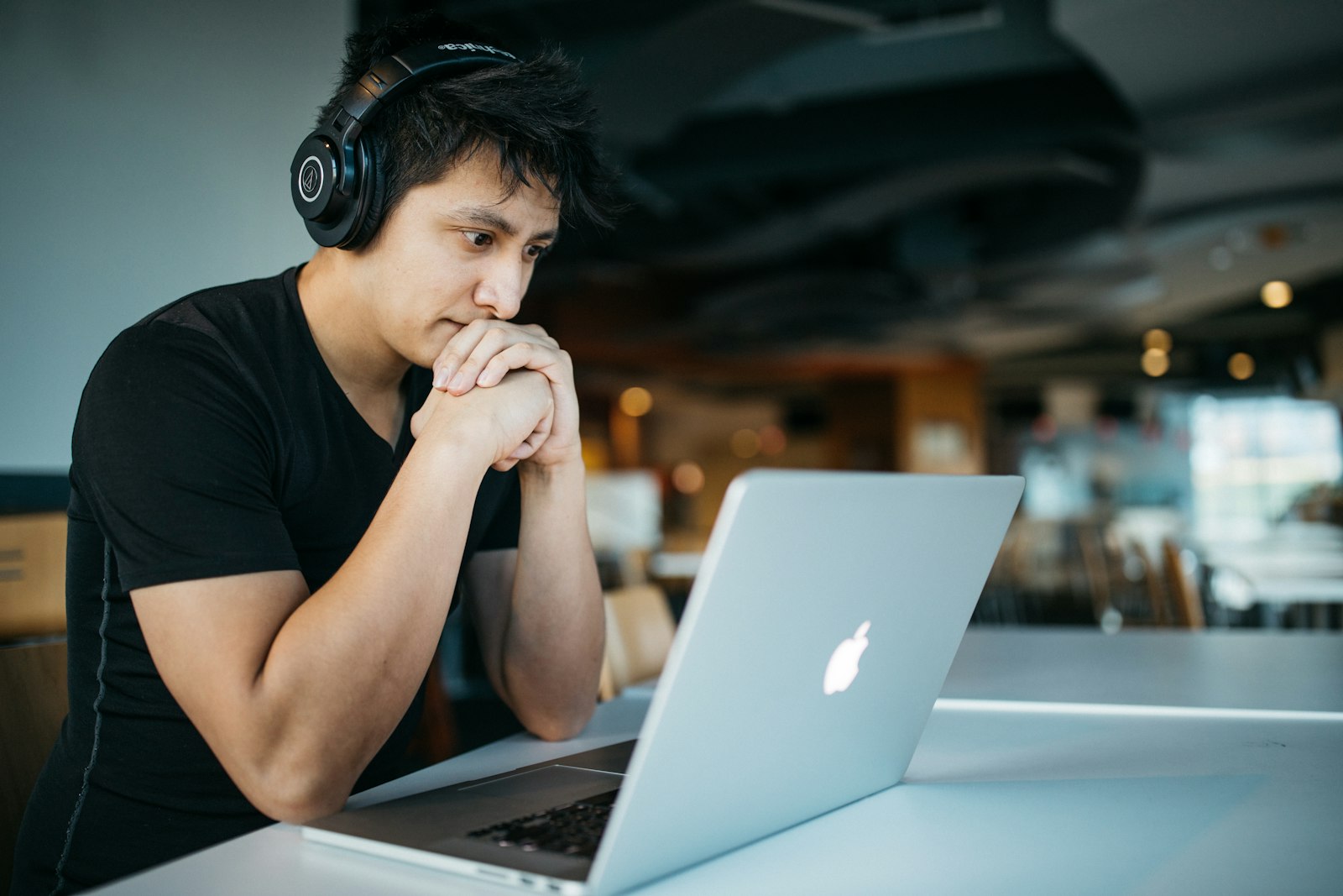 A learner wearing headphones, listening while working on a laptop