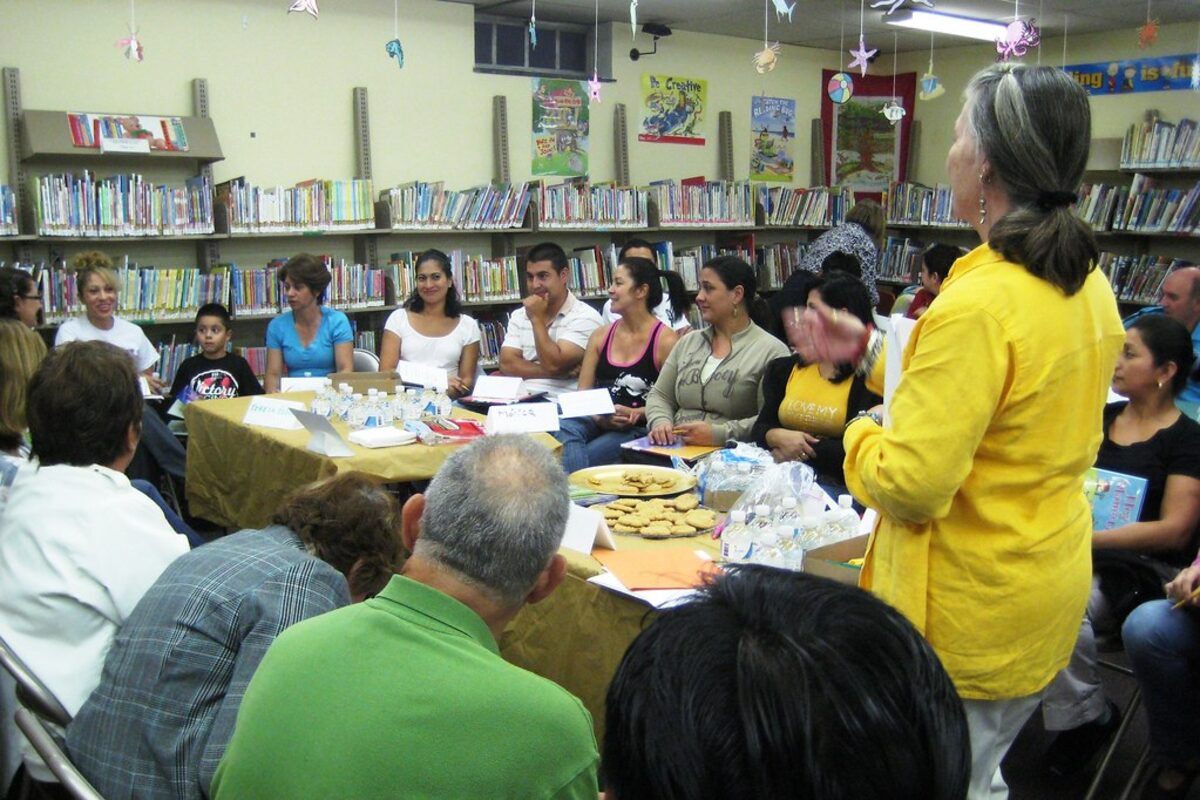 Adult learners around a table in a classroom.