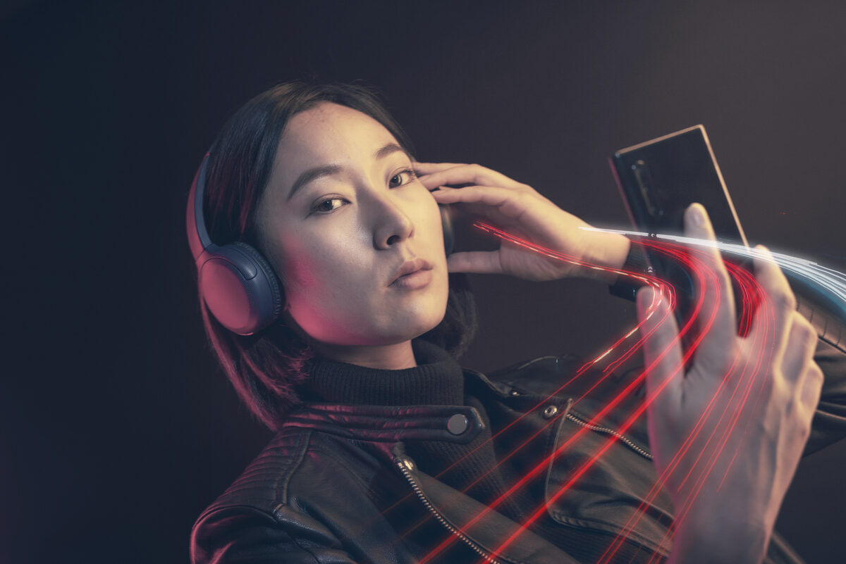 A commuter listening on headphones, phone in hand.